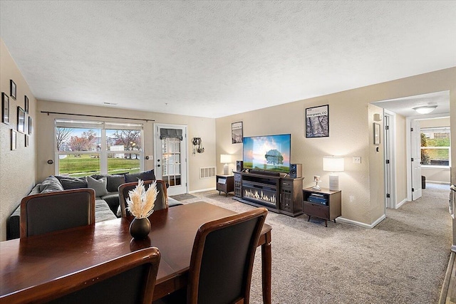 dining area with light colored carpet, visible vents, a textured wall, and a textured ceiling