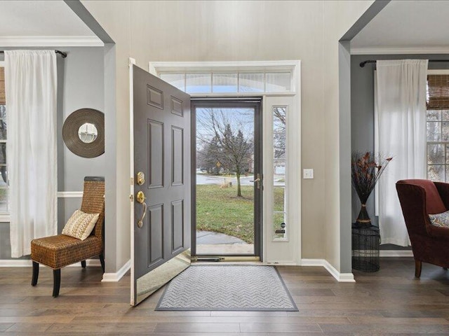 entryway featuring dark wood-type flooring, crown molding, and baseboards