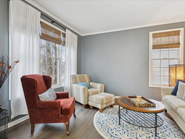 sitting room with ornamental molding and wood finished floors