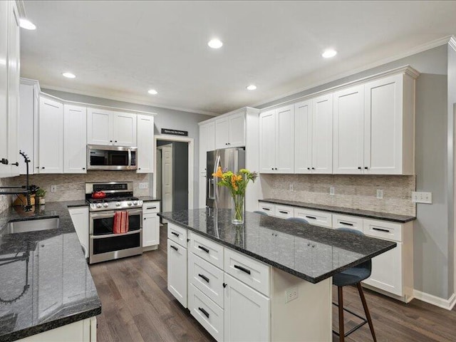 kitchen with a kitchen bar, white cabinetry, stainless steel appliances, and dark wood-type flooring