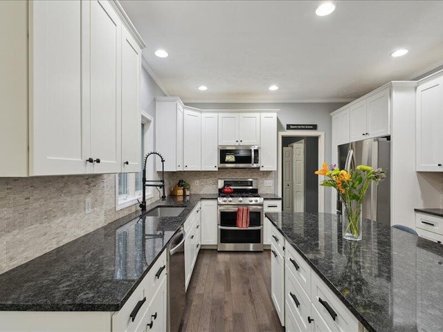 kitchen with stainless steel appliances, ornamental molding, a sink, and white cabinetry