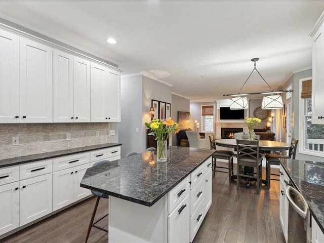 kitchen featuring a warm lit fireplace, ornamental molding, dark wood-style flooring, white cabinetry, and backsplash