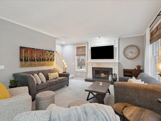 carpeted living area with baseboards, stairway, a glass covered fireplace, and crown molding