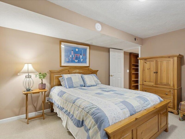 bedroom featuring light carpet, a textured ceiling, and baseboards