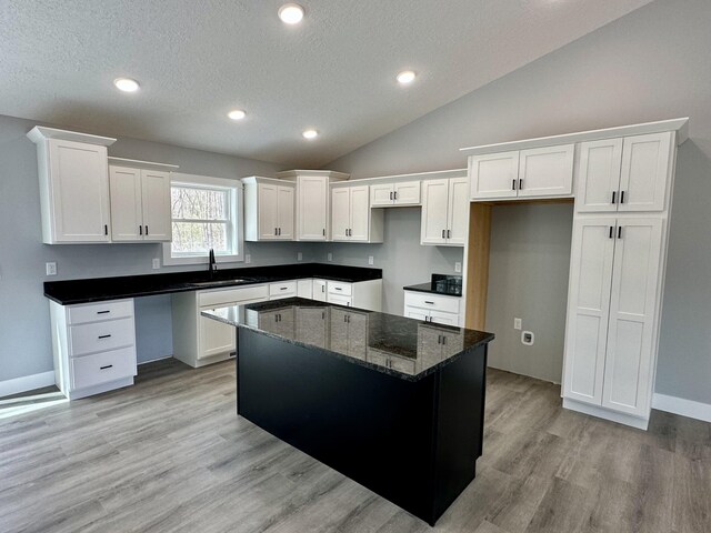 2653 Mclaughlin Ave, Muskegon, MI 49442 - kitchen with a sink, a center island, white cabinets, and a textured ceiling