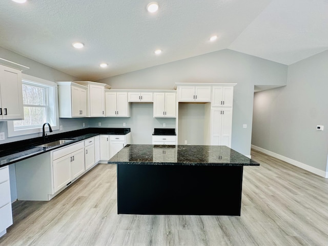 2653 Mclaughlin Ave, Muskegon, MI 49442 - kitchen with a kitchen island, white cabinets, a sink, light wood-style flooring, and vaulted ceiling