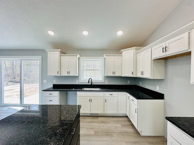 2653 Mclaughlin Ave, Muskegon, MI 49442 - kitchen with a sink, white cabinets, light wood-type flooring, and dark stone countertops