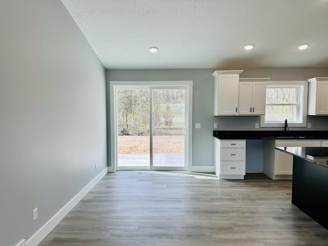 2653 Mclaughlin Ave, Muskegon, MI 49442 - kitchen with a sink, dark countertops, a textured ceiling, and white cabinetry