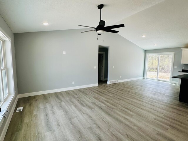 2653 Mclaughlin Ave, Muskegon, MI 49442 - unfurnished living room featuring visible vents, baseboards, a ceiling fan, light wood finished floors, and vaulted ceiling