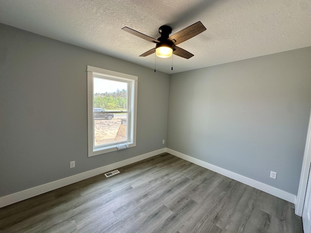2653 Mclaughlin Ave, Muskegon, MI 49442 - empty room with visible vents, baseboards, ceiling fan, dark wood-style floors, and a textured ceiling