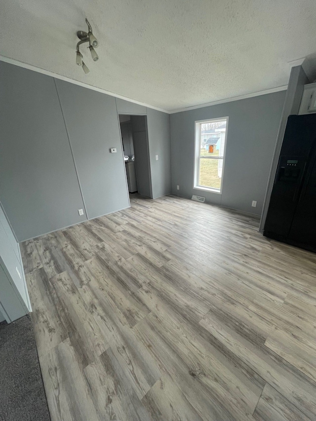 unfurnished bedroom with black refrigerator with ice dispenser, light wood-style flooring, and crown molding