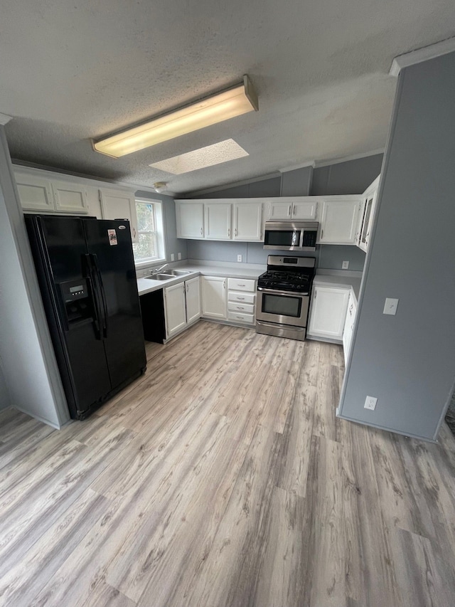 kitchen featuring light wood-style floors, white cabinetry, stainless steel appliances, and a textured ceiling