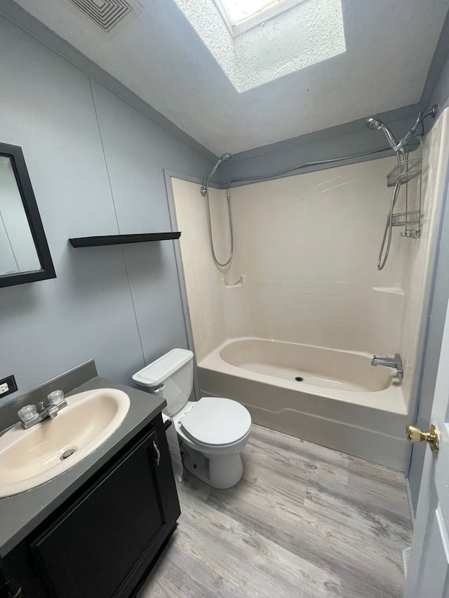 full bath featuring visible vents, toilet, wood finished floors, vanity, and washtub / shower combination