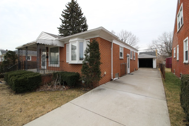 view of side of property featuring covered porch, a detached garage, an outbuilding, and brick siding