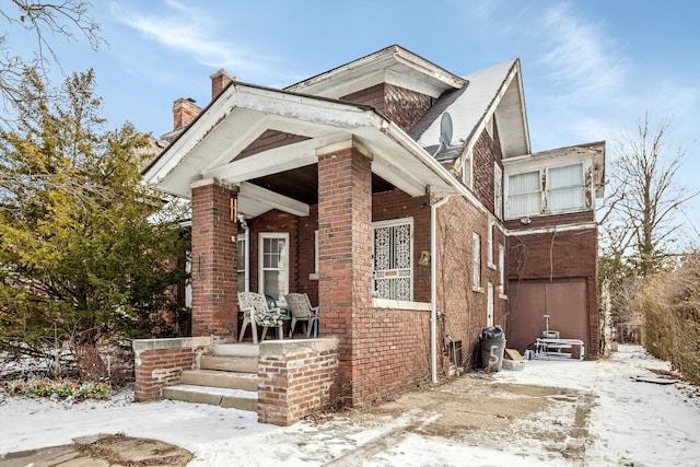 view of front of house featuring a porch, brick siding, and a garage