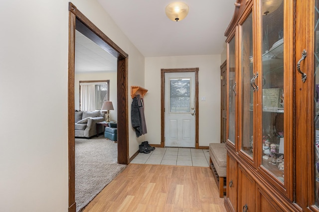 foyer with a healthy amount of sunlight, light wood-type flooring, light carpet, and baseboards