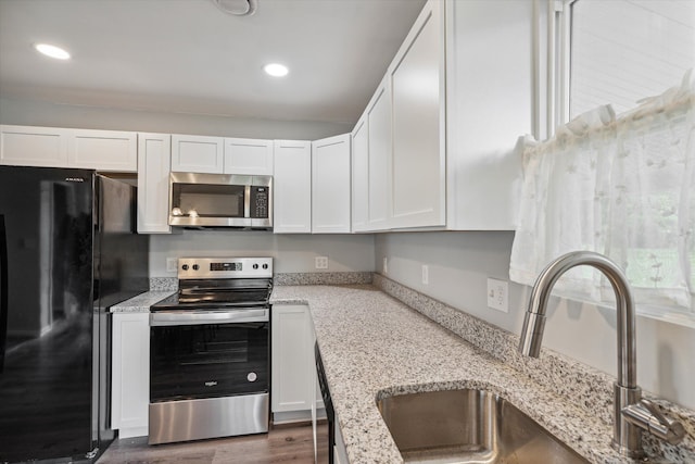 kitchen featuring light stone counters, stainless steel appliances, recessed lighting, white cabinets, and a sink