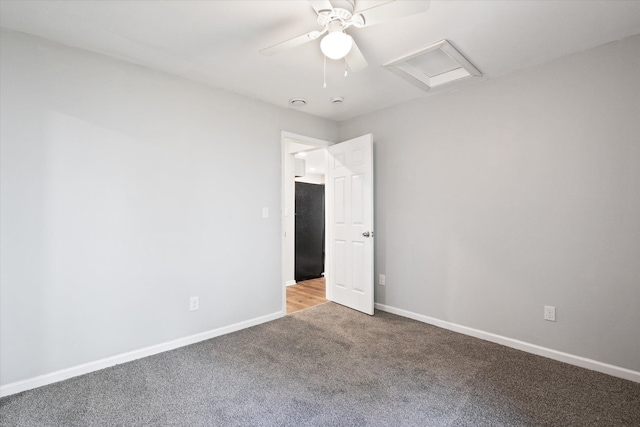 spare room with carpet, attic access, and baseboards