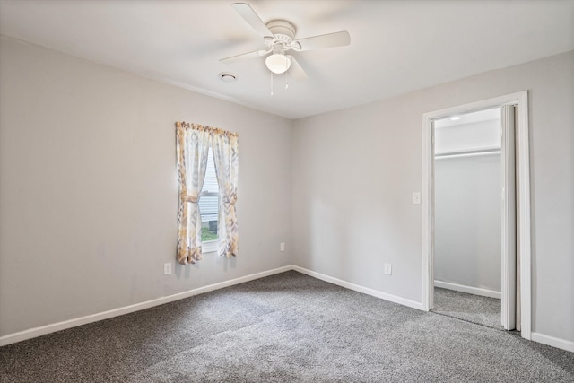 unfurnished bedroom featuring carpet floors, ceiling fan, a spacious closet, and baseboards