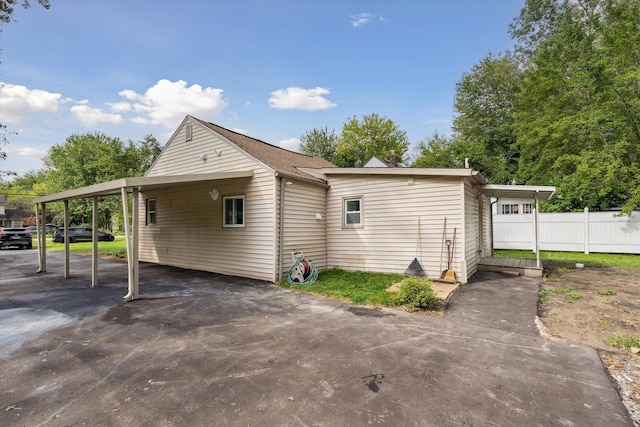 view of property exterior with driveway, fence, and a carport