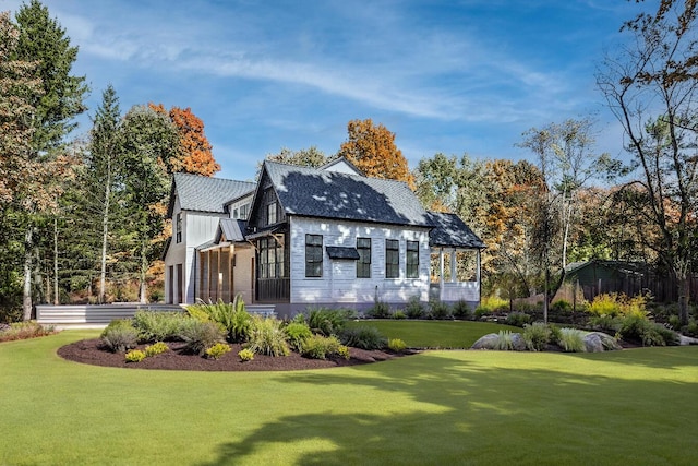 rear view of property with driveway, a garage, a lawn, metal roof, and a standing seam roof