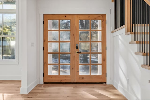 doorway with stairs, french doors, baseboards, and light wood-style floors