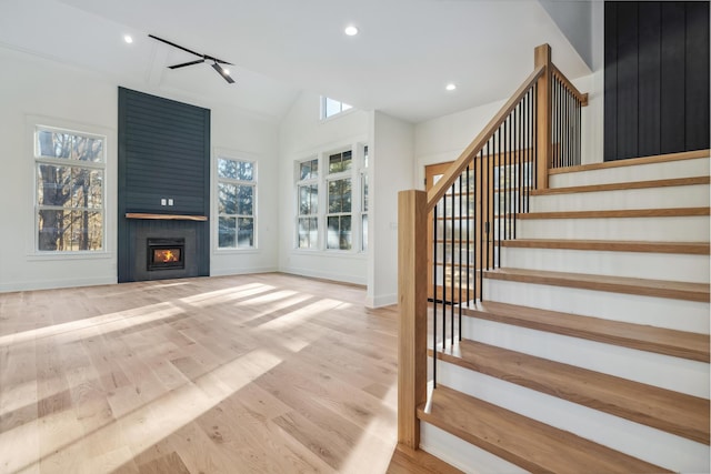 unfurnished living room with a fireplace, lofted ceiling, wood finished floors, baseboards, and stairs