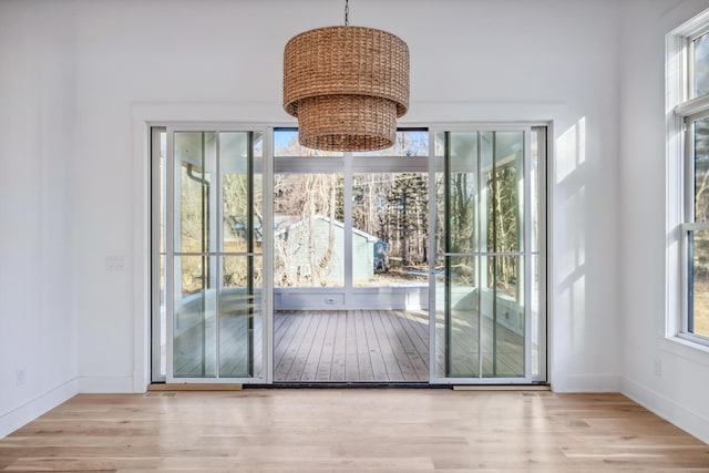 doorway with a chandelier, wood finished floors, and baseboards