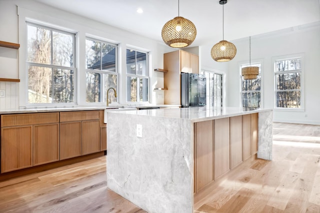 kitchen featuring a healthy amount of sunlight, light wood-style floors, open shelves, and black refrigerator