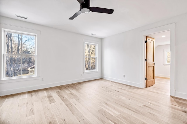 unfurnished room featuring light wood-type flooring, a healthy amount of sunlight, and visible vents