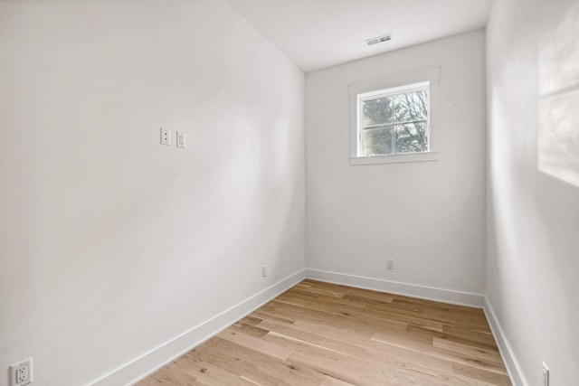 spare room featuring light wood-style floors, visible vents, and baseboards