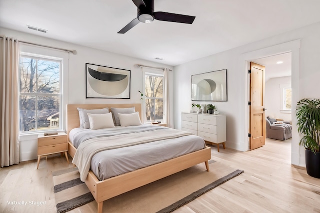 bedroom featuring light wood-style flooring, multiple windows, visible vents, and ceiling fan