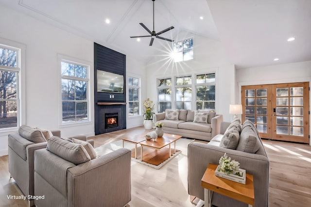 living room with a healthy amount of sunlight, light wood-style floors, a fireplace, and high vaulted ceiling