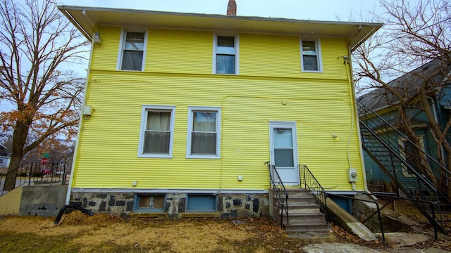 rear view of house featuring entry steps and a chimney