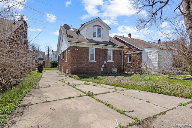 view of property exterior featuring brick siding and driveway