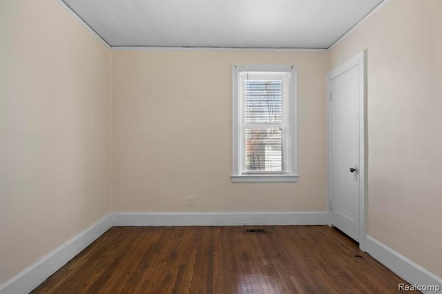 empty room featuring dark wood-style flooring and baseboards