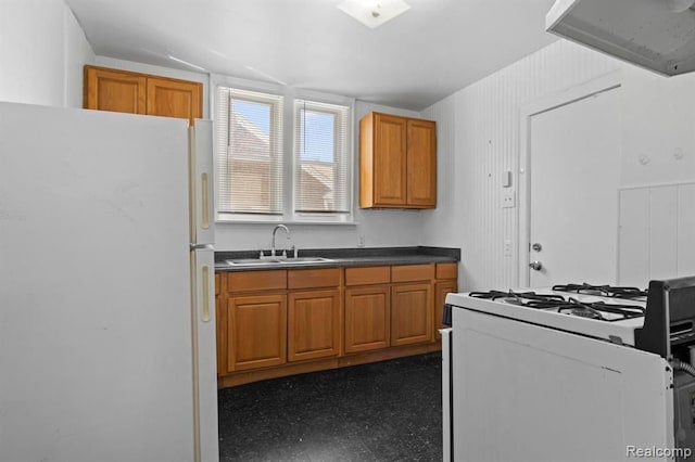 kitchen featuring white appliances, brown cabinetry, and a sink