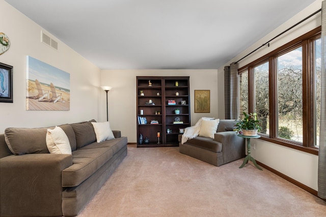 living area with baseboards, visible vents, and light colored carpet