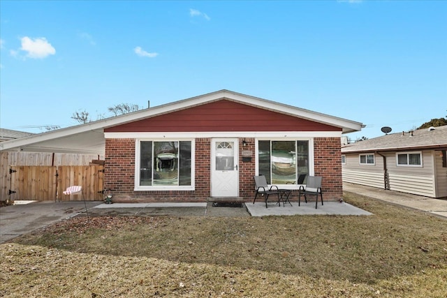 view of front of property with a front yard, brick siding, and fence