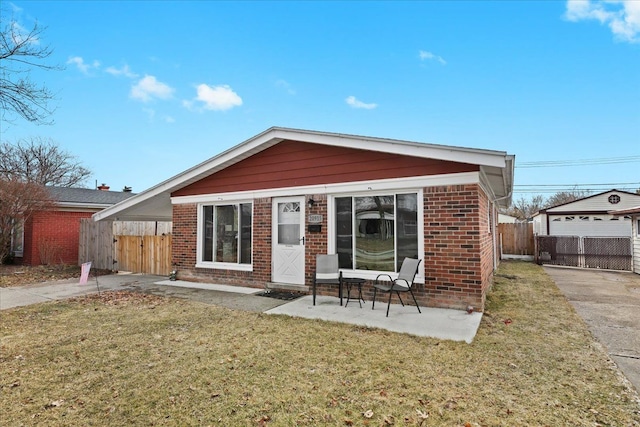 back of property featuring a gate, fence, a yard, an outdoor structure, and brick siding