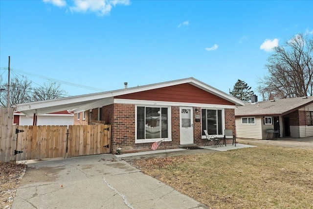 view of front of home with brick siding, a patio, a gate, fence, and a front yard