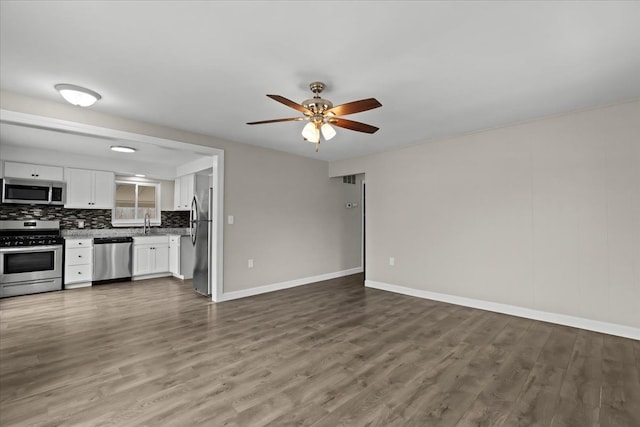 kitchen with tasteful backsplash, appliances with stainless steel finishes, open floor plan, wood finished floors, and white cabinetry