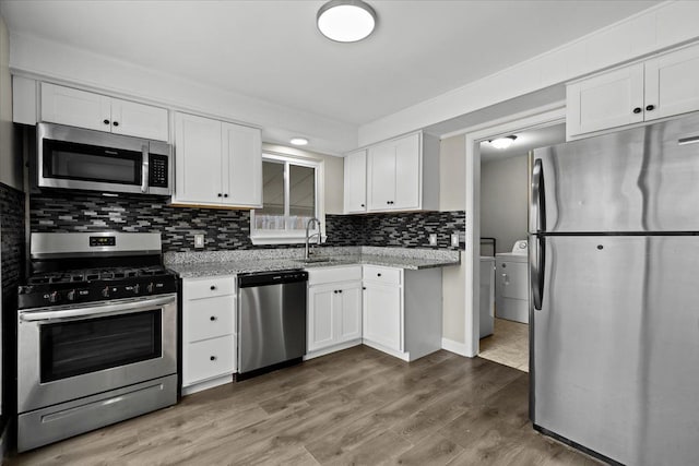 kitchen featuring a sink, white cabinetry, stainless steel appliances, and separate washer and dryer