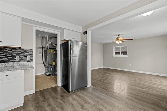 kitchen with dark wood-type flooring, white cabinets, backsplash, and freestanding refrigerator