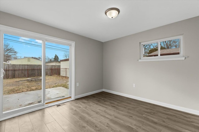 unfurnished room featuring visible vents, baseboards, and wood finished floors