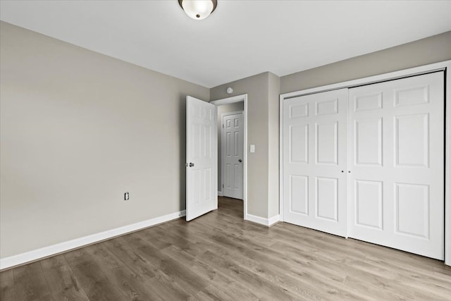 unfurnished bedroom featuring light wood-style floors, a closet, and baseboards