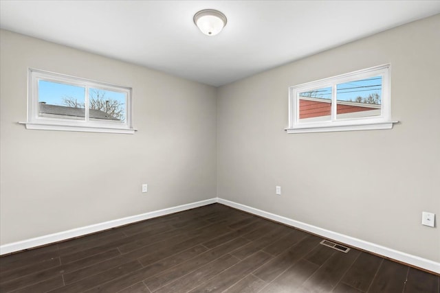 empty room with dark wood-type flooring, a wealth of natural light, and baseboards