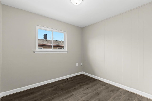 unfurnished room featuring baseboards, visible vents, and dark wood finished floors