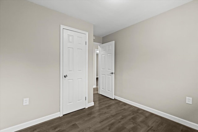 unfurnished bedroom featuring dark wood-style flooring and baseboards