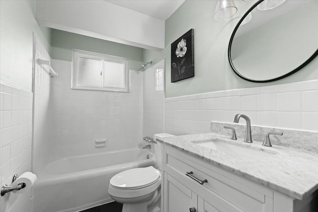 full bath featuring a wainscoted wall, tile walls, shower / bathing tub combination, toilet, and vanity